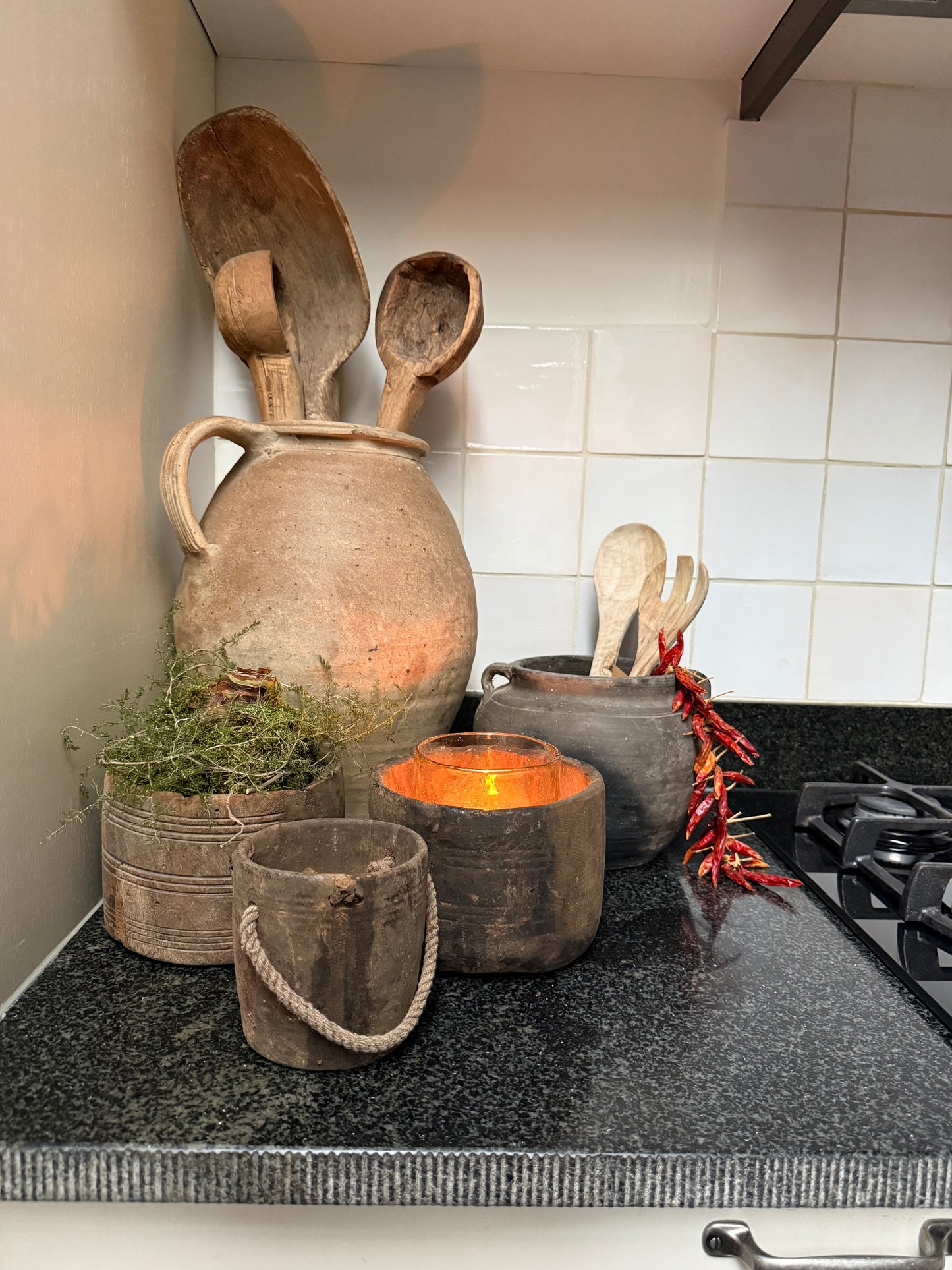 Authentieke handgemaakte houten accessoires en potten op een landelijke keukenkast met sfeerlicht.