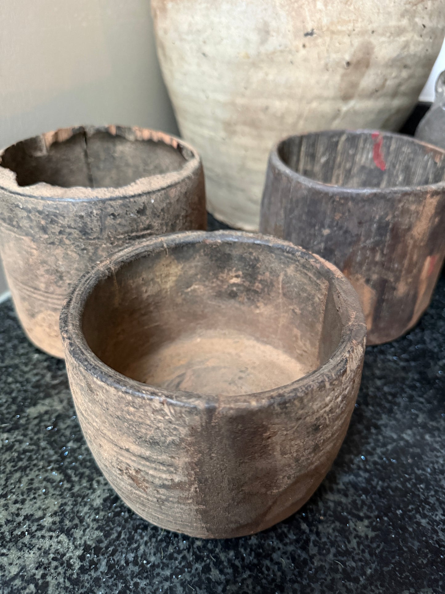 Drie authentieke, handgemaakte houten potten op zwart oppervlak, landelijk en sober interieur