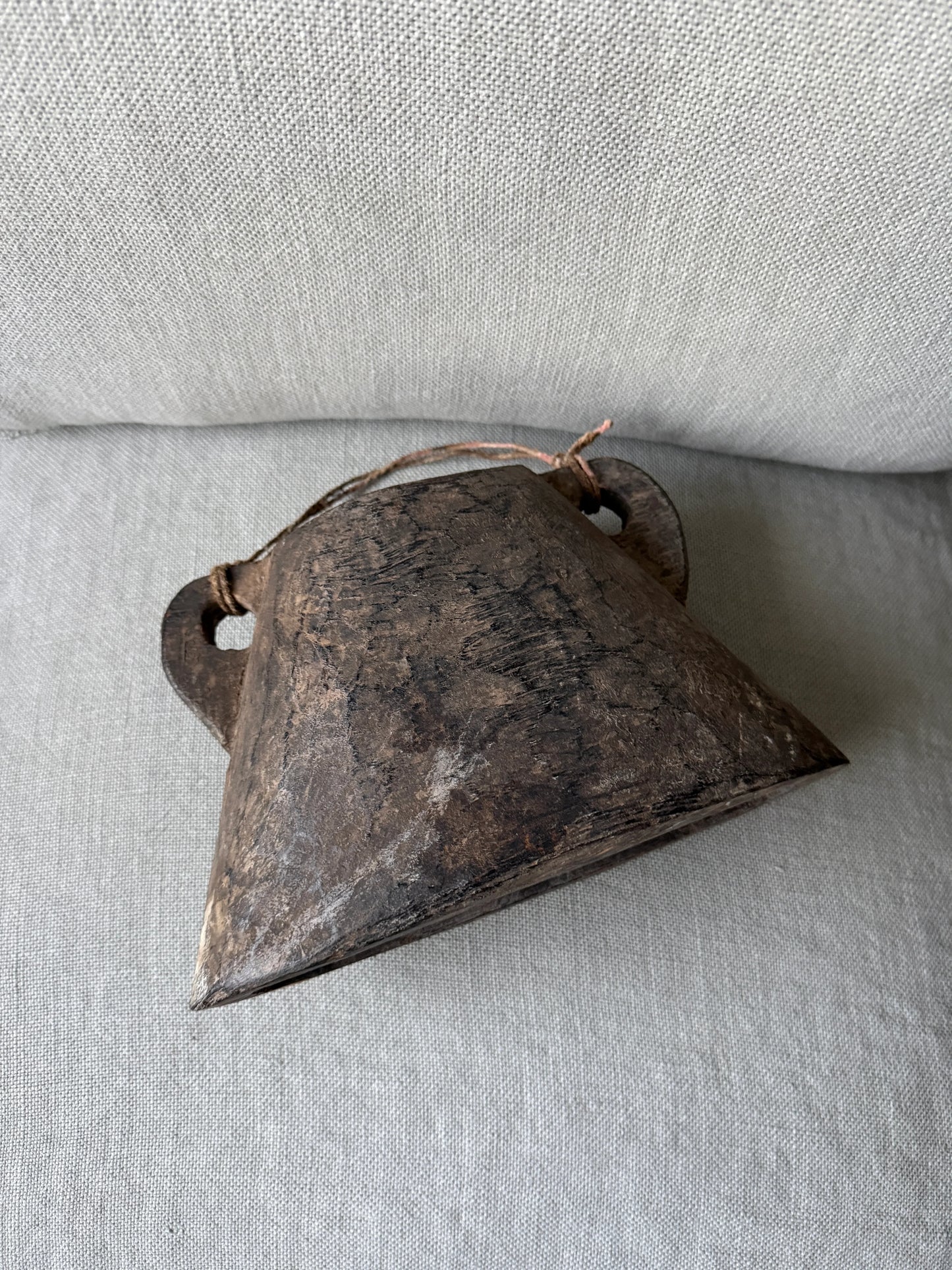 Authentieke, handgemaakte Nepalese bel op linnen bank, sober landelijk woonaccessoire