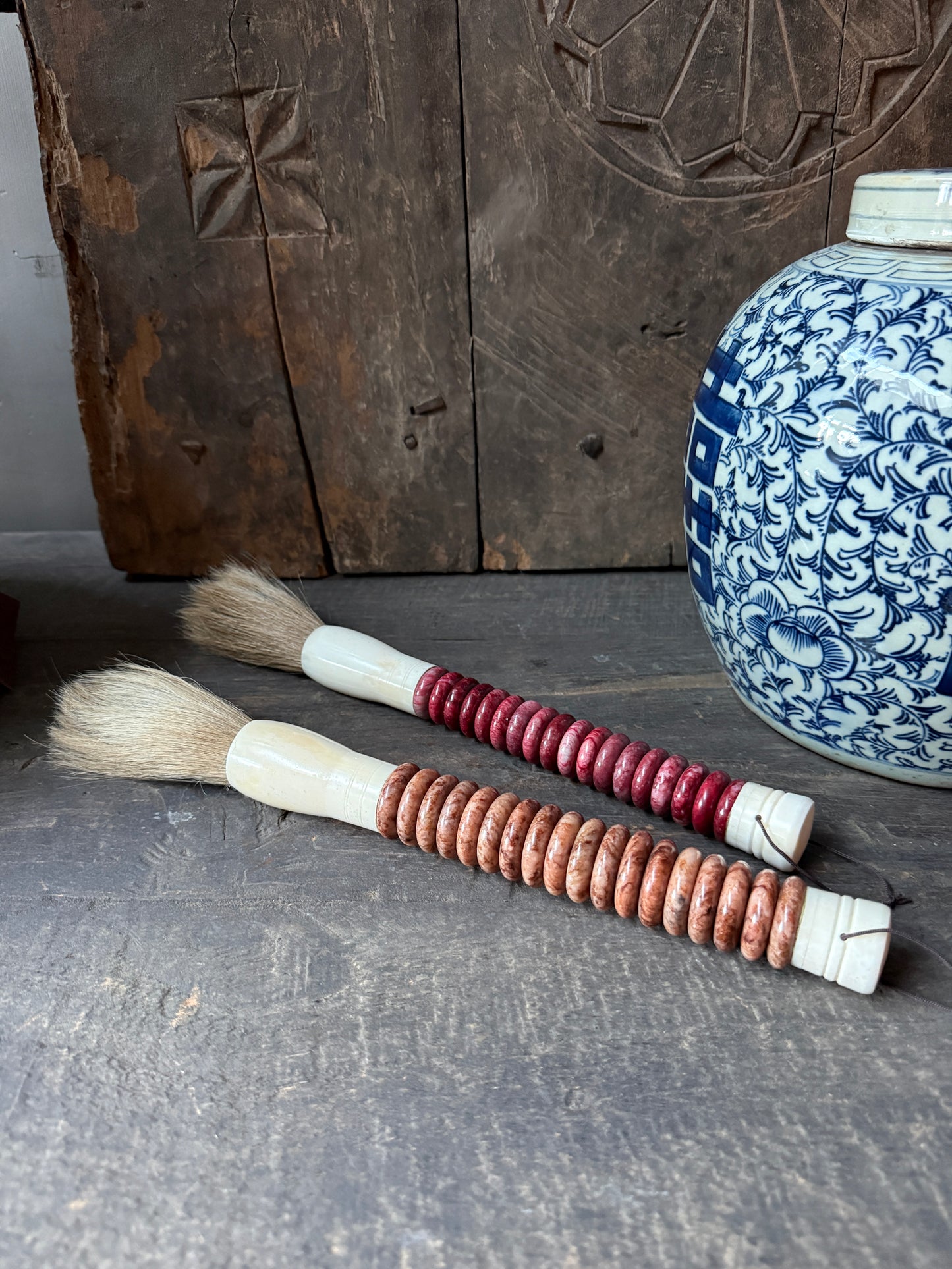 Handgemaakte kwasten met houten kralen en blauw-witte vaas, landelijk sober interieur