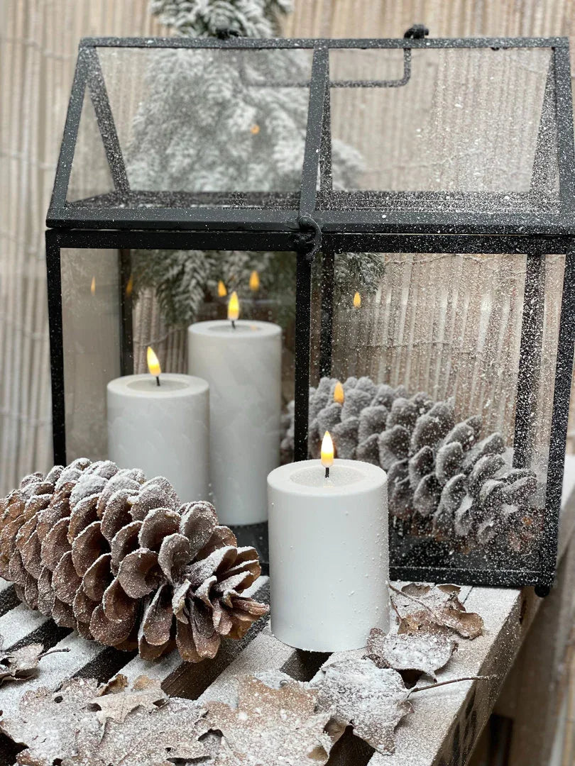 Witte kaarsen en dennenappels met sneeuw in glazen lantaarn, landelijk en sober interieurdecoratie.