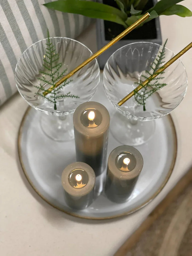 Stijlvolle landelijke decoratie met glazen, groene takjes en rustieke kaarsen op dienblad