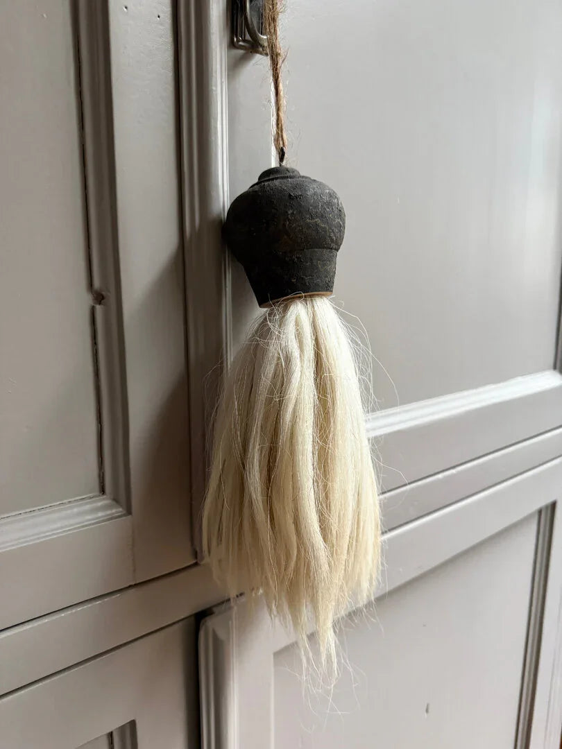 Handgemaakte landelijke kwast met zwarte kop, hangend aan een sobere kastdeur