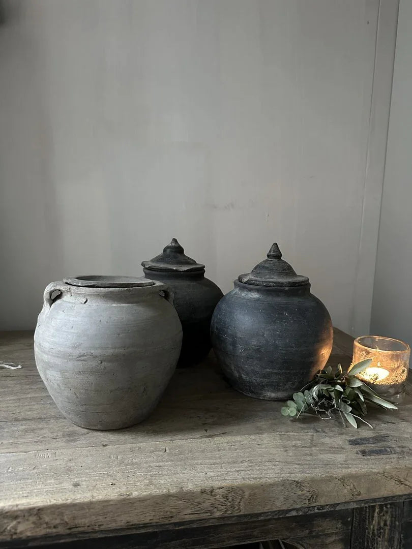 Set van authentieke handgemaakte potjes met deksel op houten tafel, sober landelijk interieur