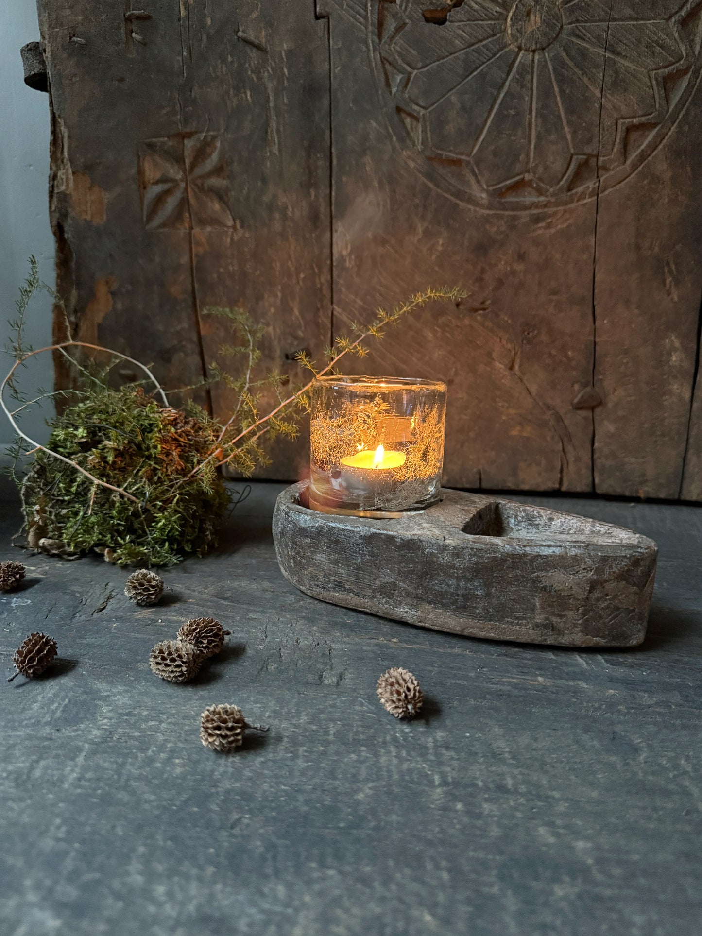 Sfeervolle setting met handgemaakt houten accessoire, kaarsje en natuurlijke decoratie, landelijk interieur.