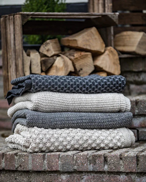 Stapel grijze gebreide plaids op stenen trap, landelijke woonaccessoire My Sober Home