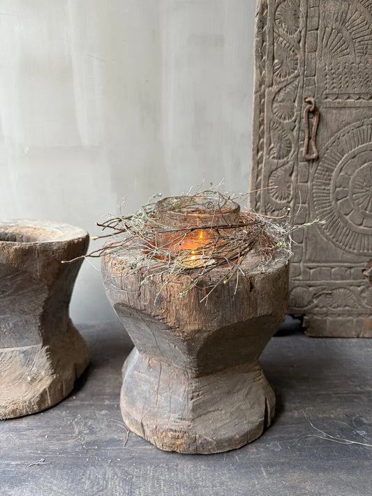 Authentieke houten vijzel met natuurlijke decoratie en vlam, sober landelijk interieur