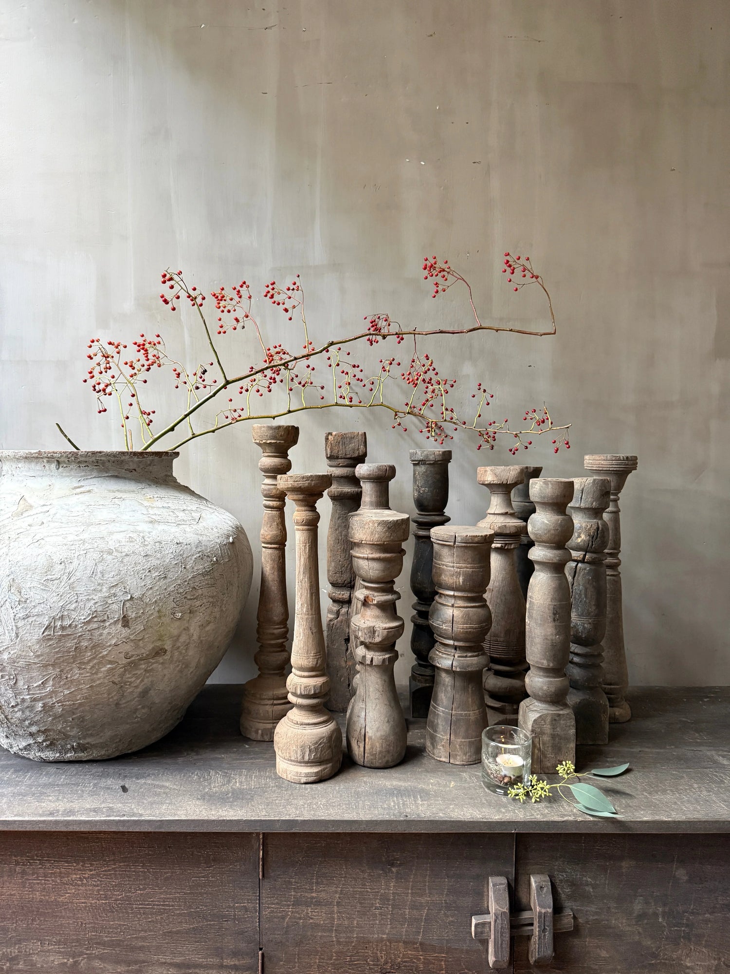Authentieke houten balusters en grote aardewerken vaas met rode bessen, landelijk sober interieur