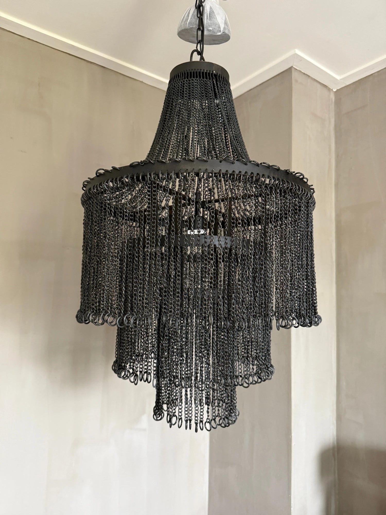 Authentieke industriële hanglamp van zwart metaal met kettingdetails in sober interieur