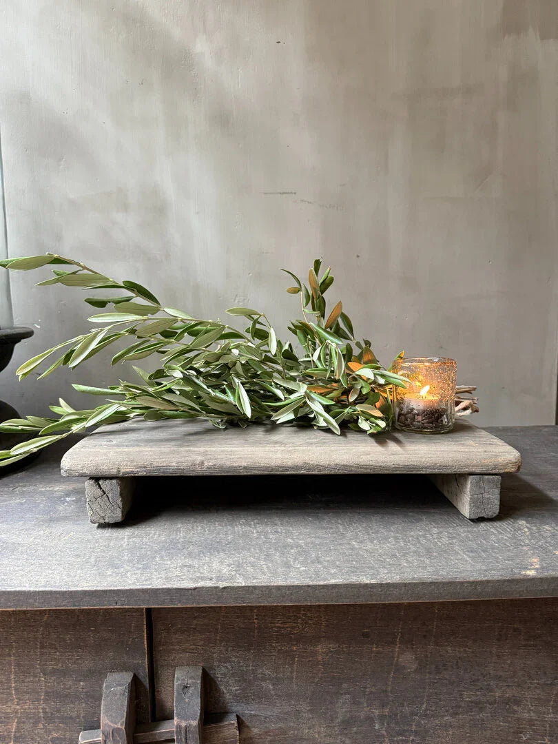 Authentiek houten bajot tafeltje met groen takje en windlicht, sober landelijk interieur accent