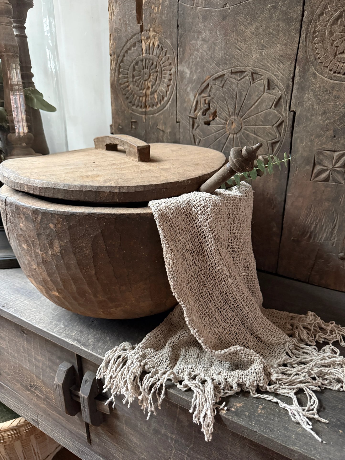 Handgemaakte houten pot met deksel, linnen doek en landelijke decoratie op een sobere kast