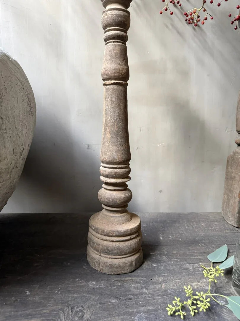 Authentieke houten baluster kandelaar op donkere tafel, landelijk en sober interieurdecoratie.