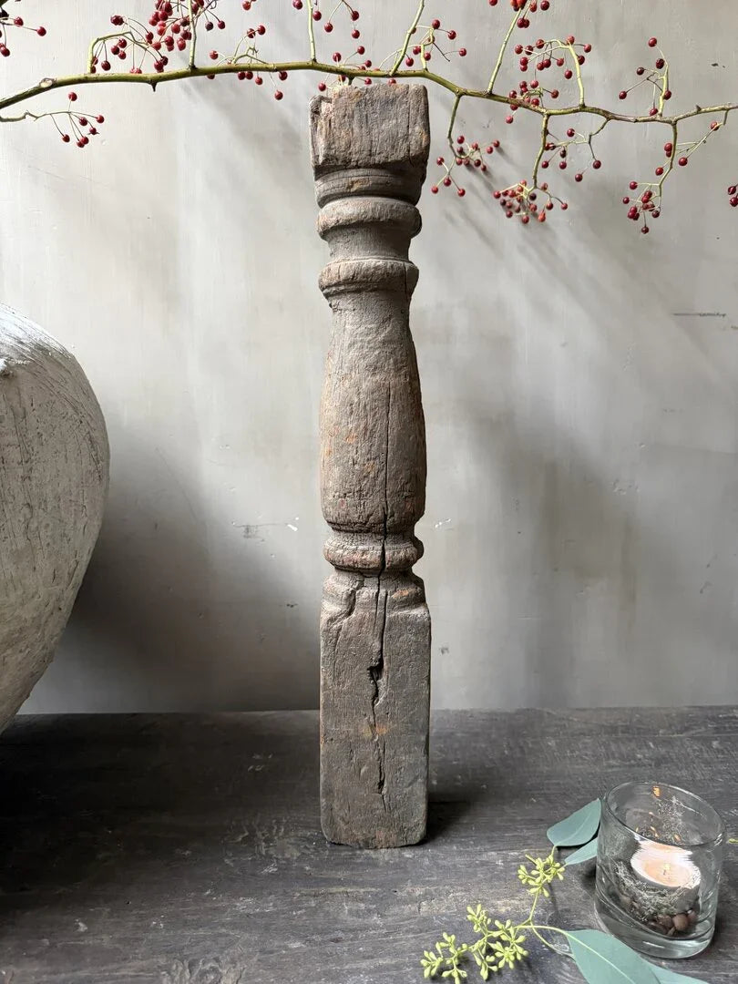 Authentieke handgemaakte houten baluster op donkere tafel, landelijke woonaccessoire