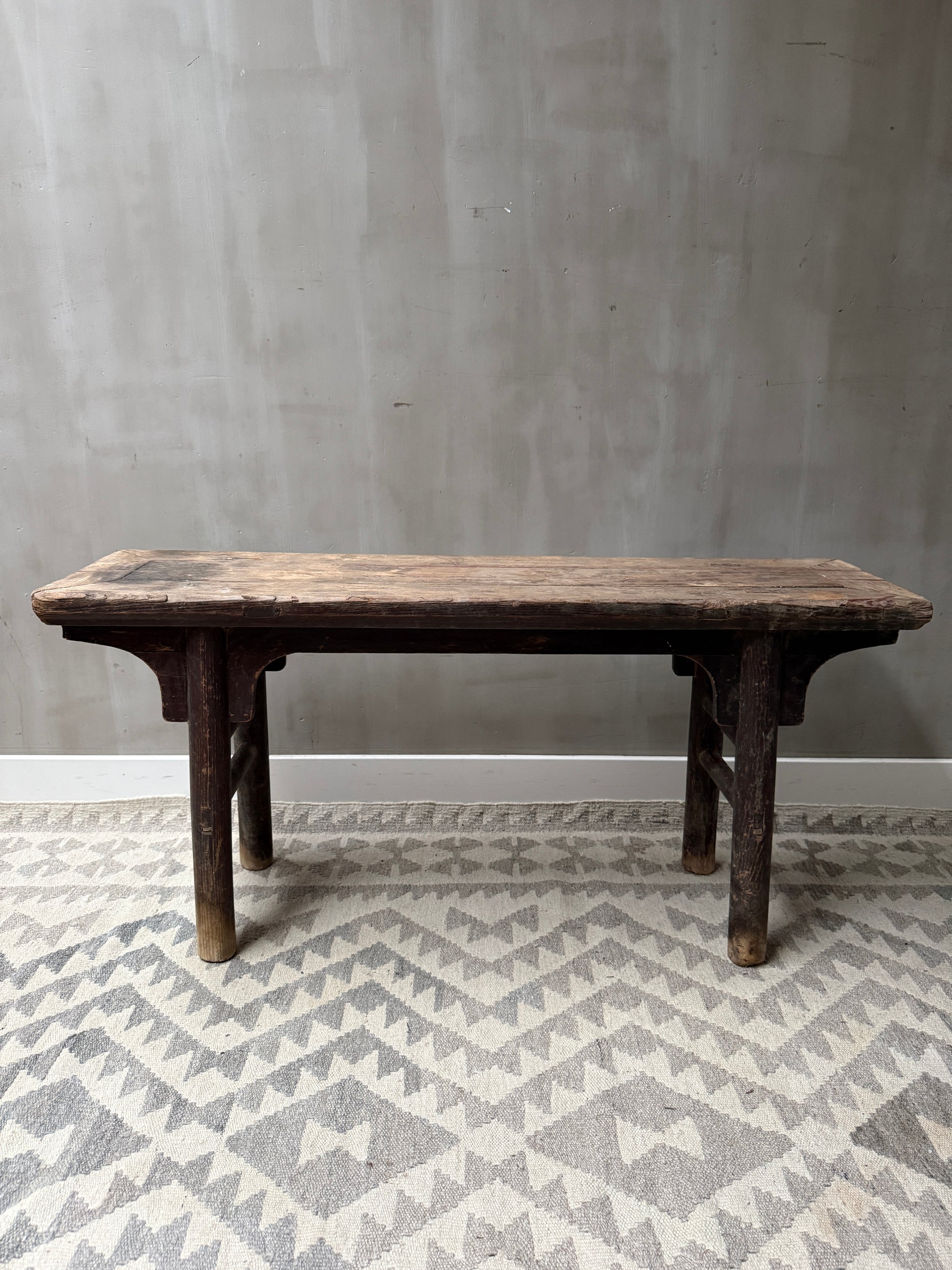Authentiek handgemaakt houten bankje, landelijk en sober, op een licht grijs vloerkleed
