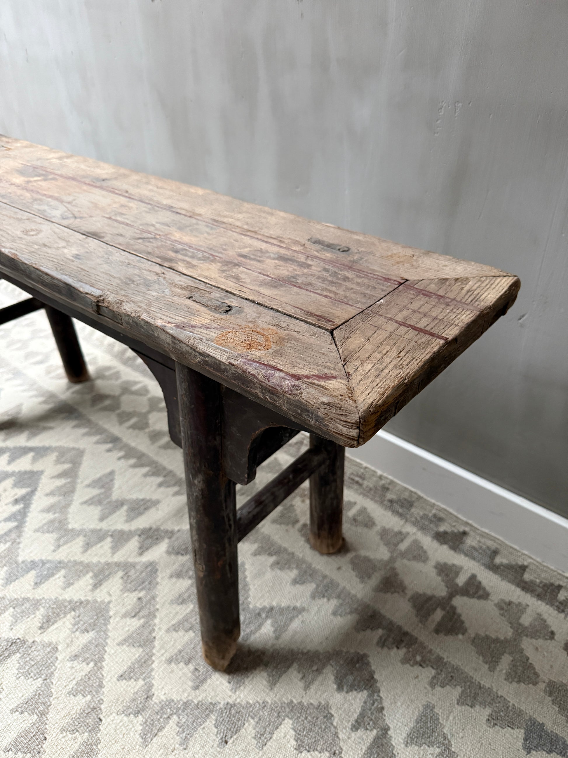 Authentiek houten bankje met doorleefde uitstraling op vintage vloerkleed, sober interieur