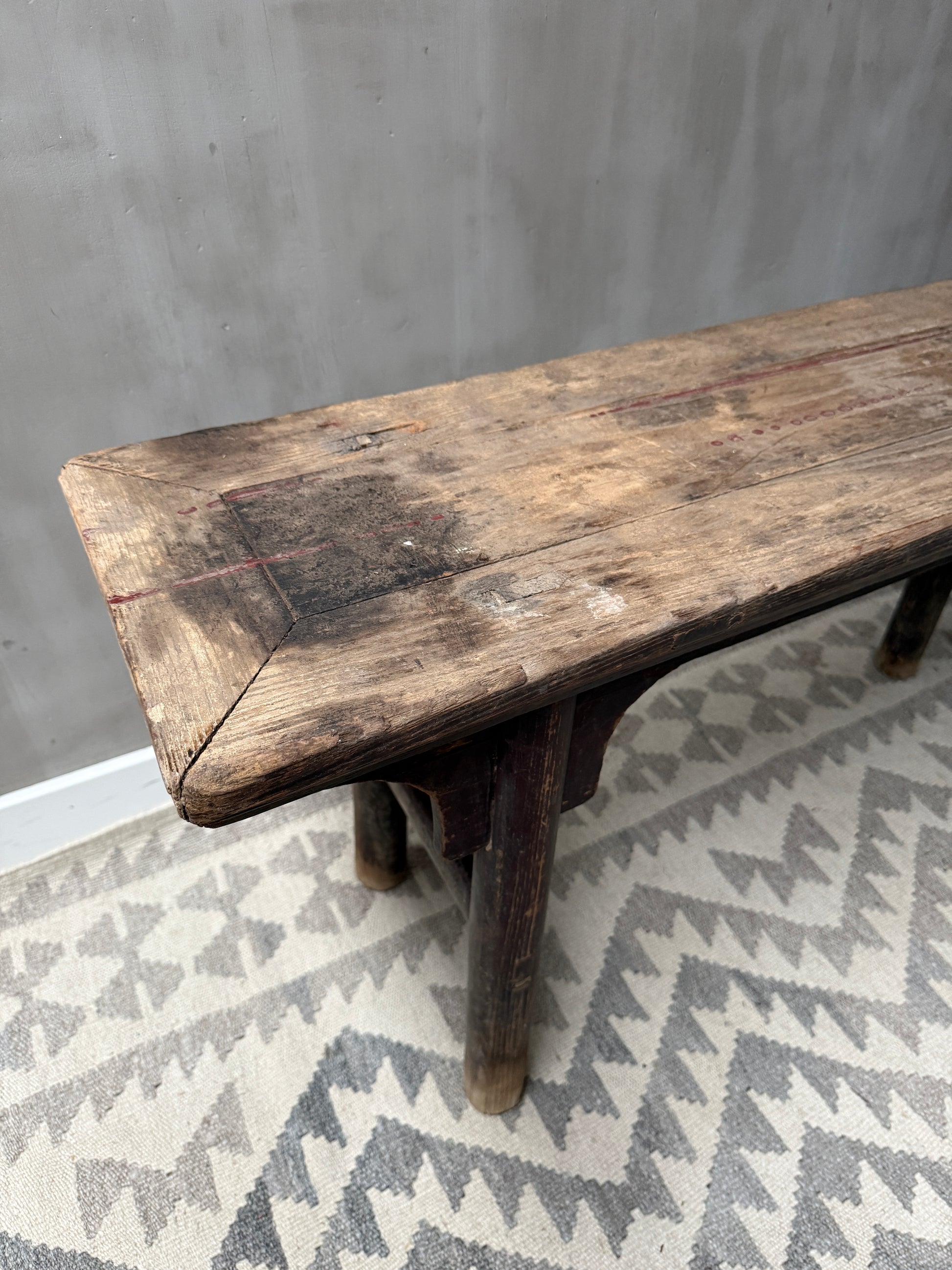 Authentiek handgemaakt houten bankje op oosters vloerkleed, sober landelijk interieur