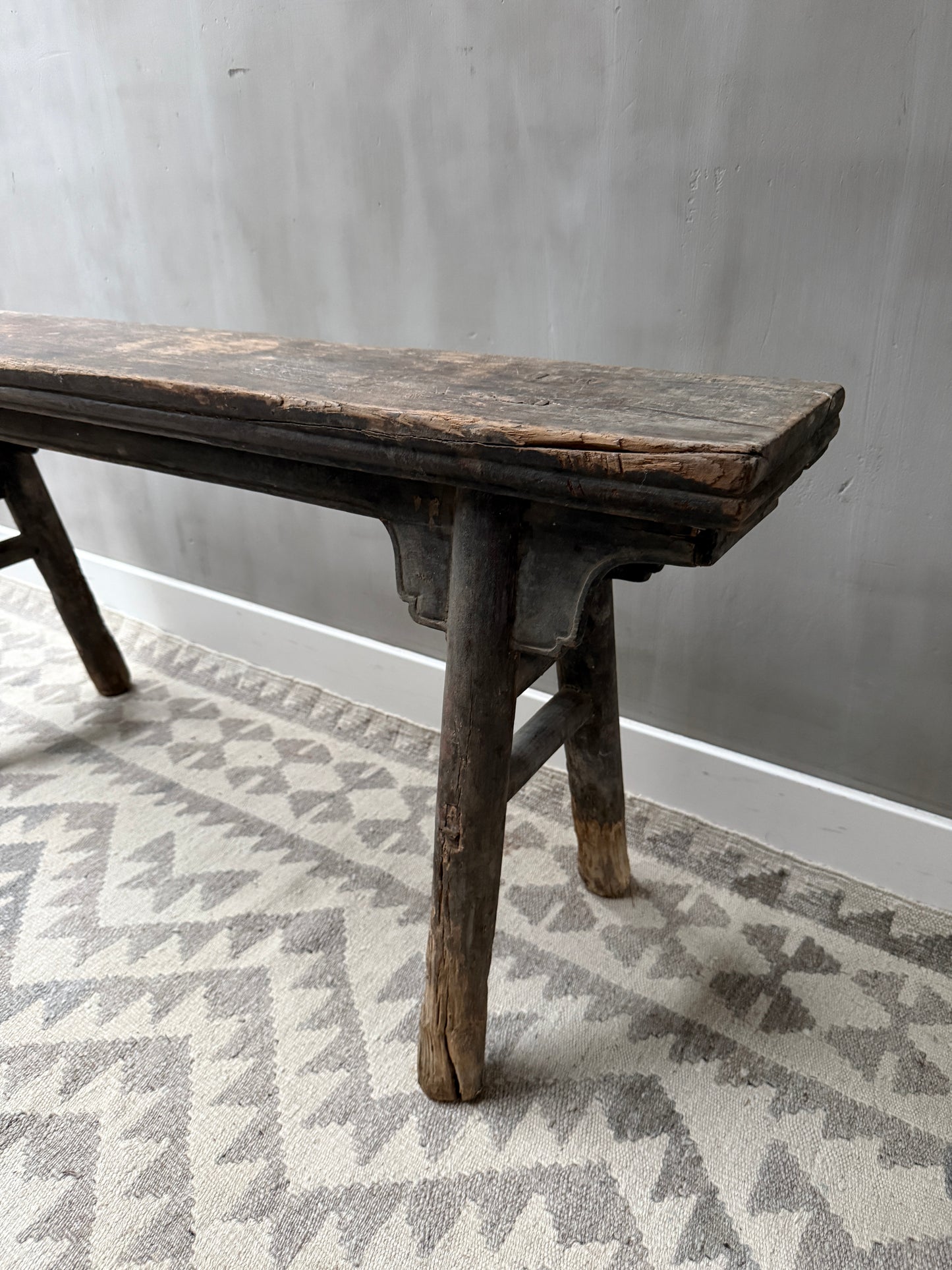 Authentiek handgemaakt houten bankje met verweerde look, landelijk sober interieur.