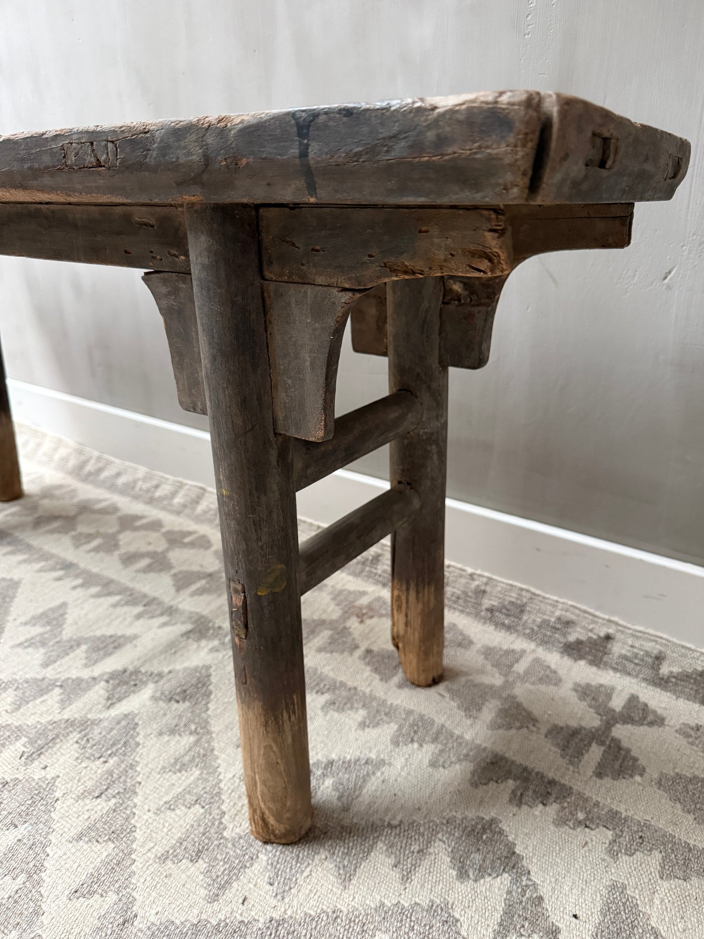 Authentiek handgemaakt houten bankje op een licht vloerkleed, landelijk en sober interieur