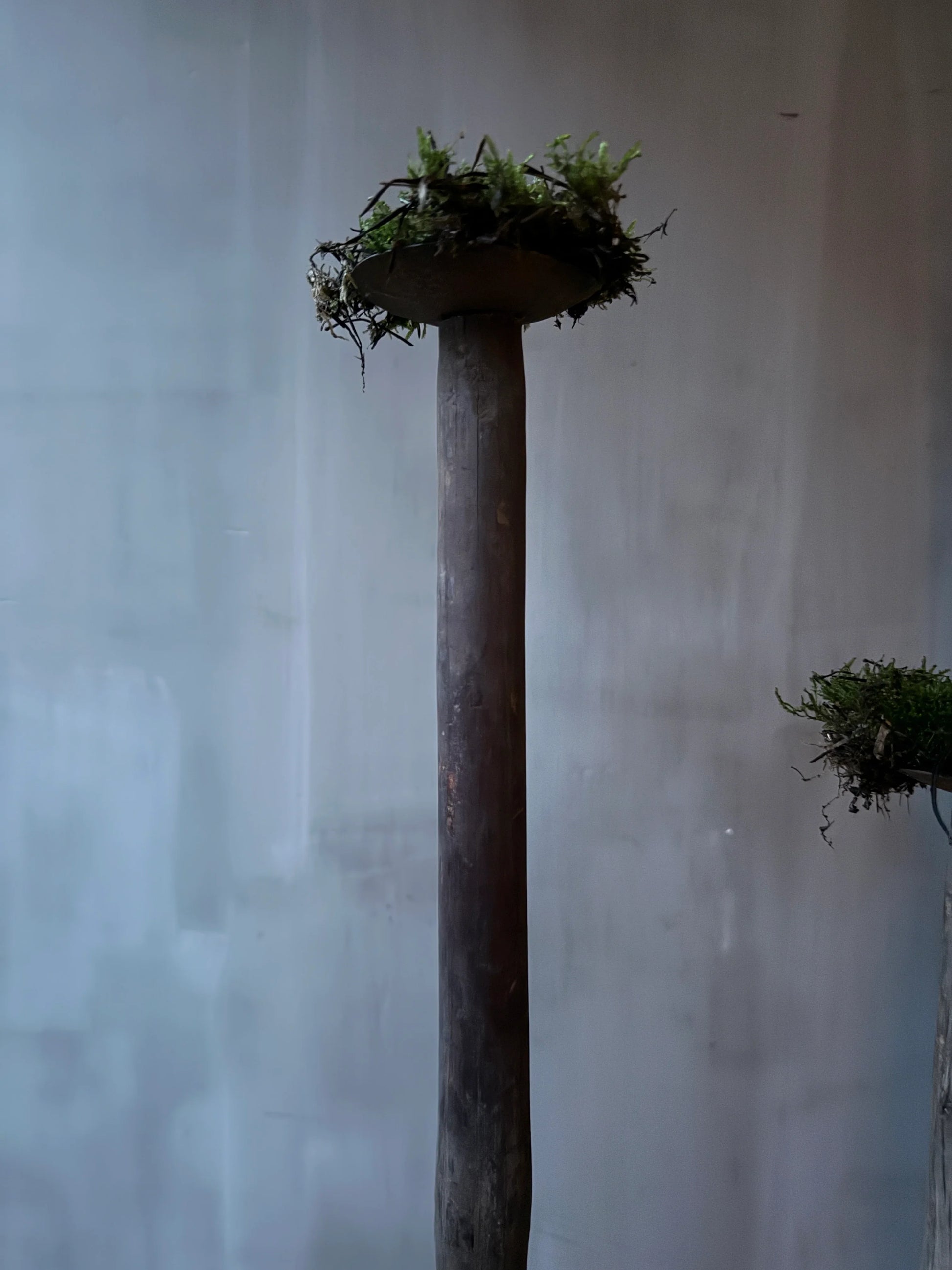 Handgemaakte houten boterstamper met mosdecoratie, sobere landelijke woonaccessoire.