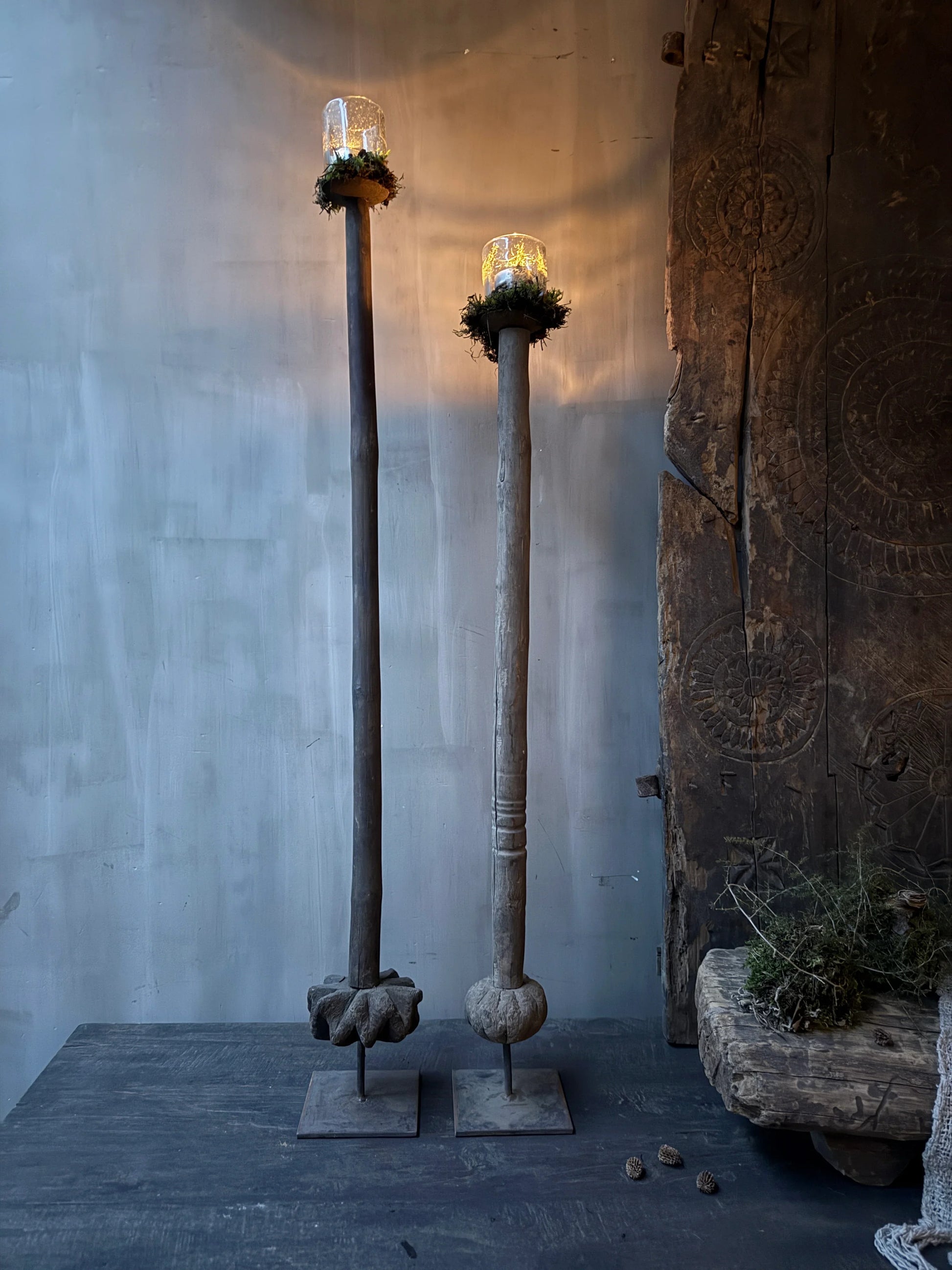 Twee houten, handgemaakte boterstampers met glazen stolpen op standaard in een sober, landelijk interieur.