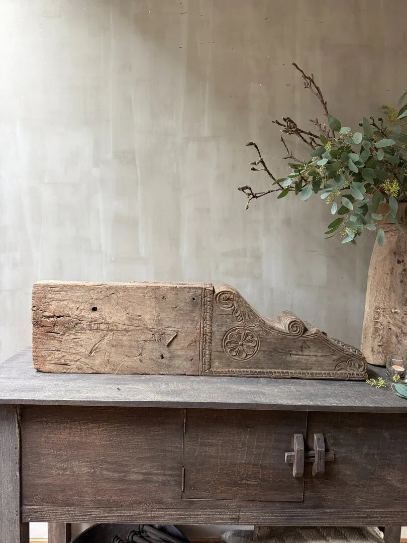 Authentiek houten bouwornament met sierlijke gravures op een rustieke tafel, landelijk en sober interieur