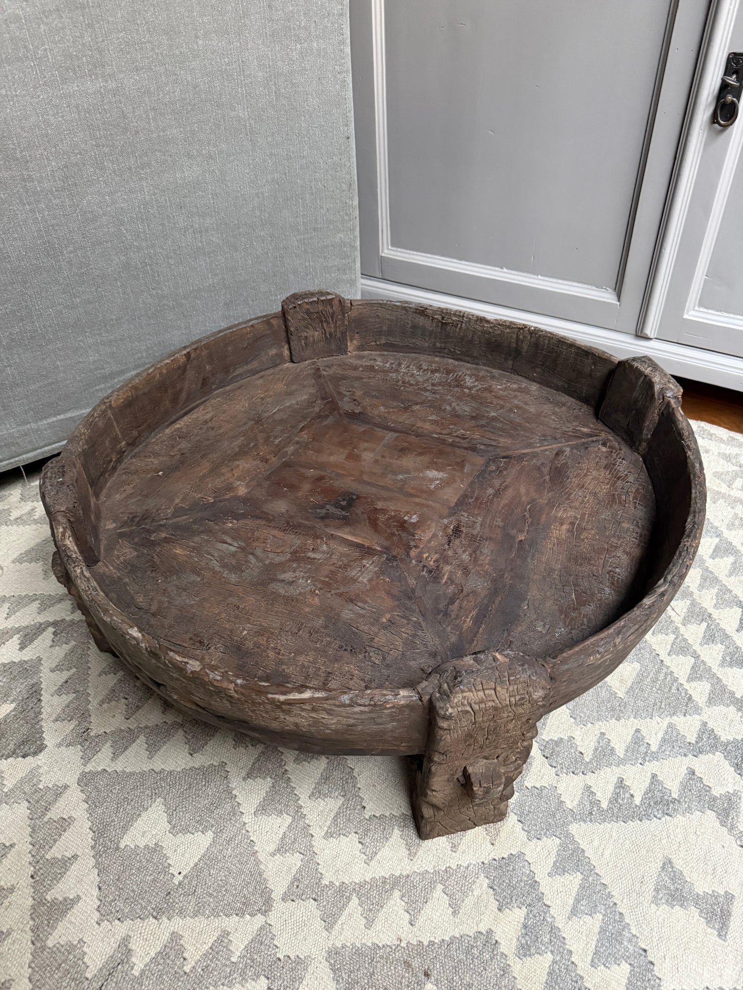 Authentieke handgemaakte houten chakki tafel op vloerkleed, sober landelijk interieur