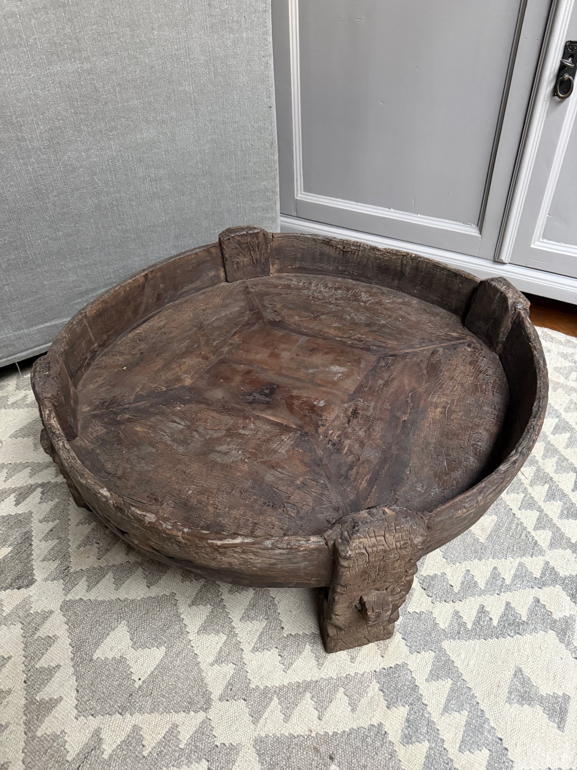 Authentieke handgemaakte houten chakki tafel op vloerkleed, sober landelijk interieur