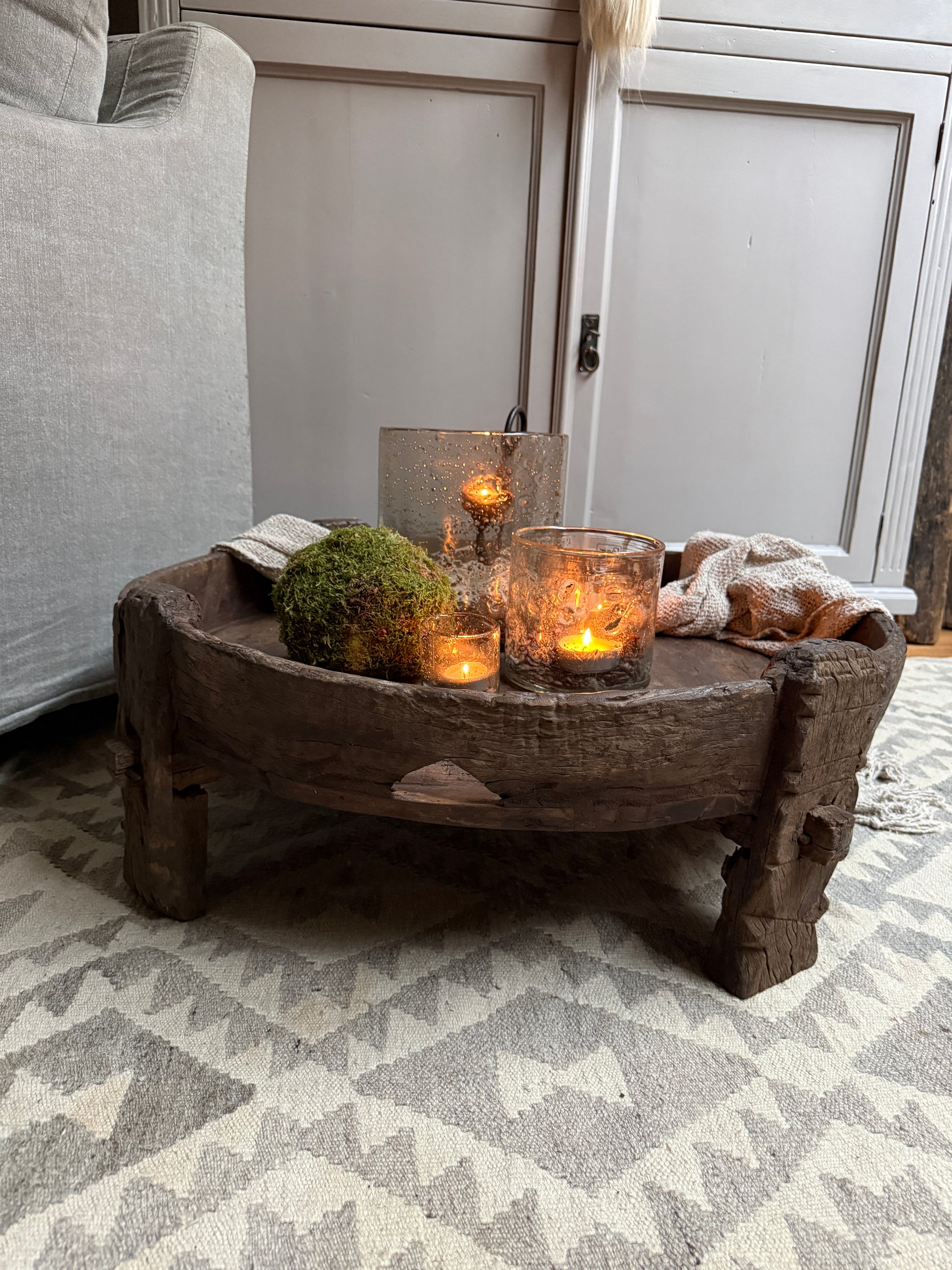 Authentieke houten chakki tafel met kaarsen, mos en landelijke accessoires in sober interieur