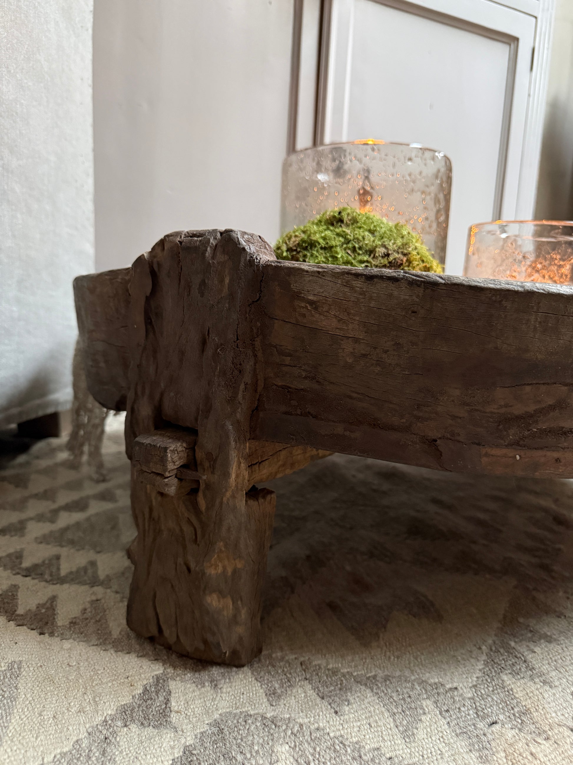 Handgemaakte houten chakkitafel met kandelaars en mos, sfeervol landelijk interieur