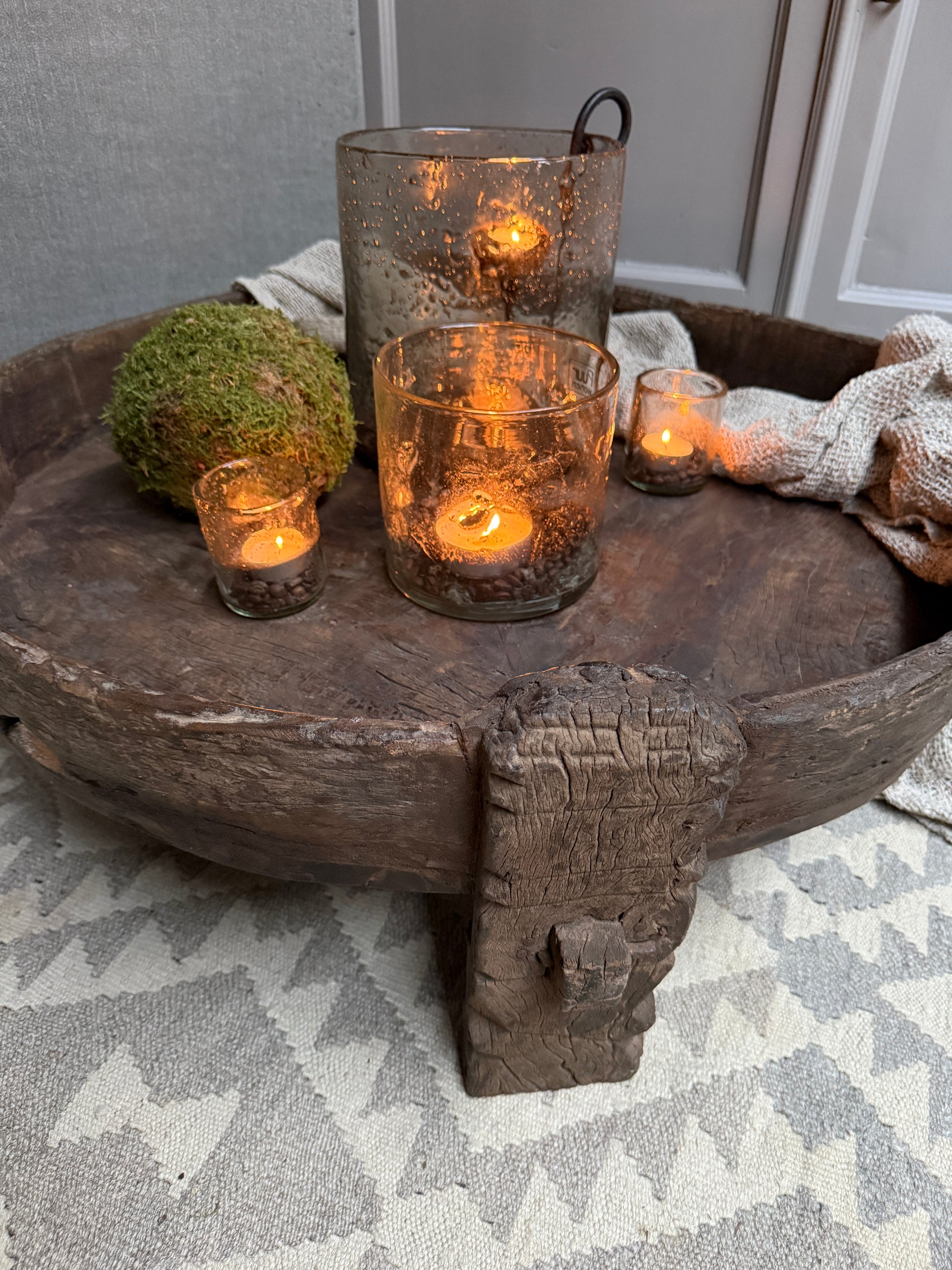 Houten chakkitafel met handgemaakte windlichten, mosbal en landelijke woonaccessoires