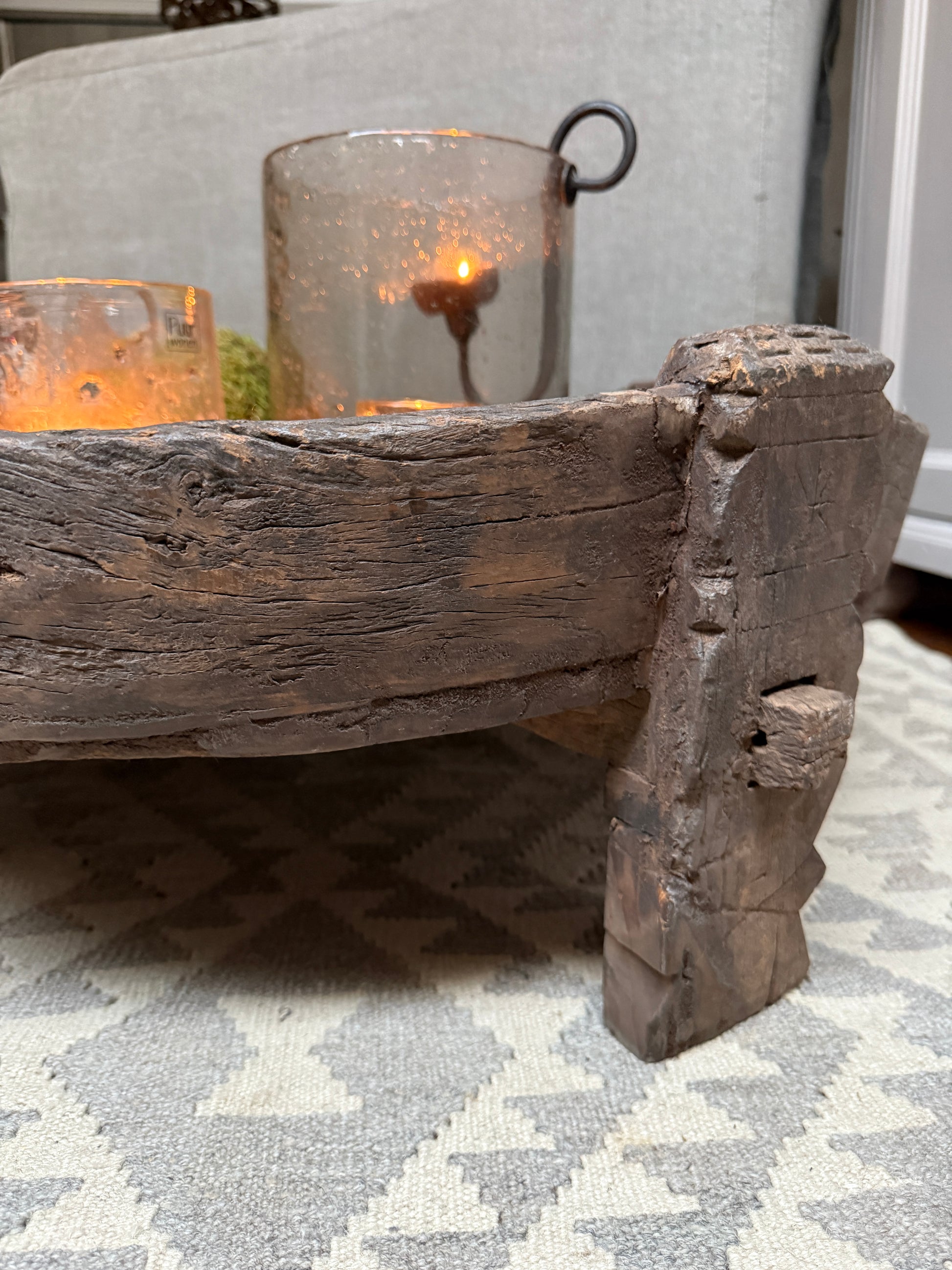 Authentieke handgemaakte houten chakkitafel met sfeerlicht op tapijt, sober landelijk interieur