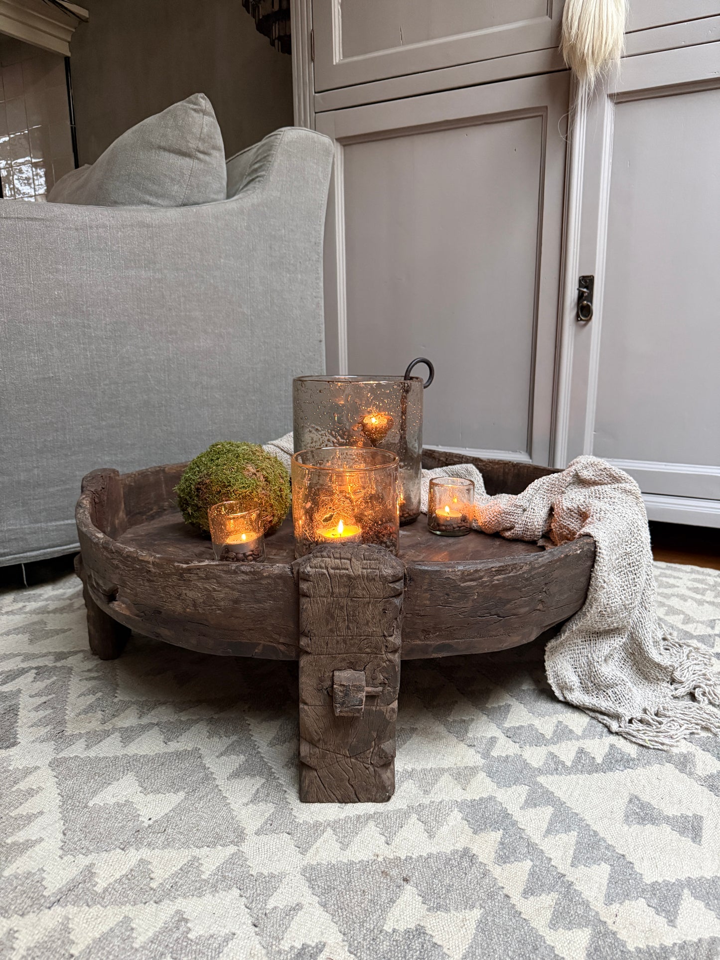 Authentieke houten chakkitafel met kaarsen, mos en plaid in een sober landelijk interieur