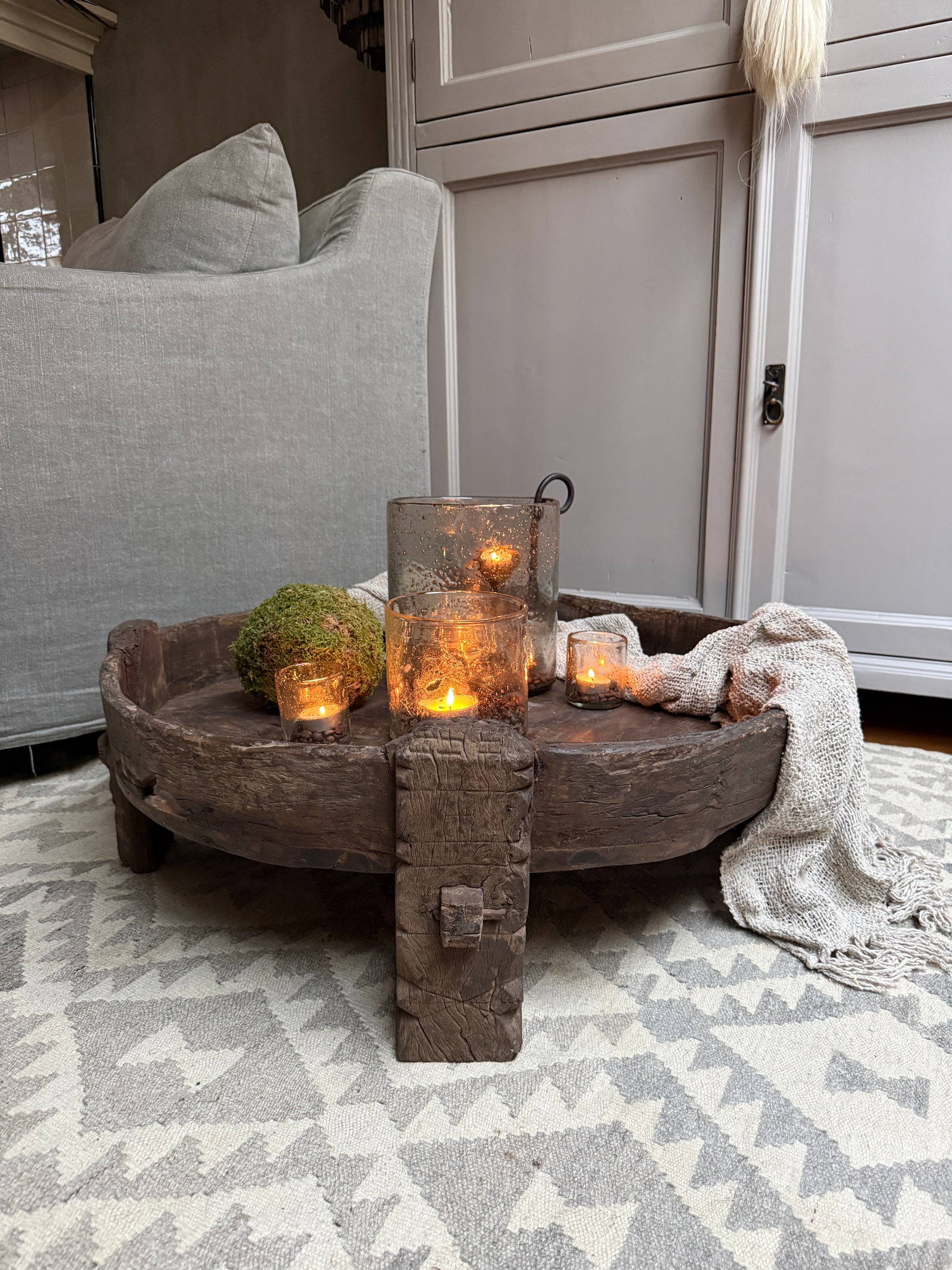 Authentieke houten chakkitafel met kaarsen, mos en plaid in een sober landelijk interieur