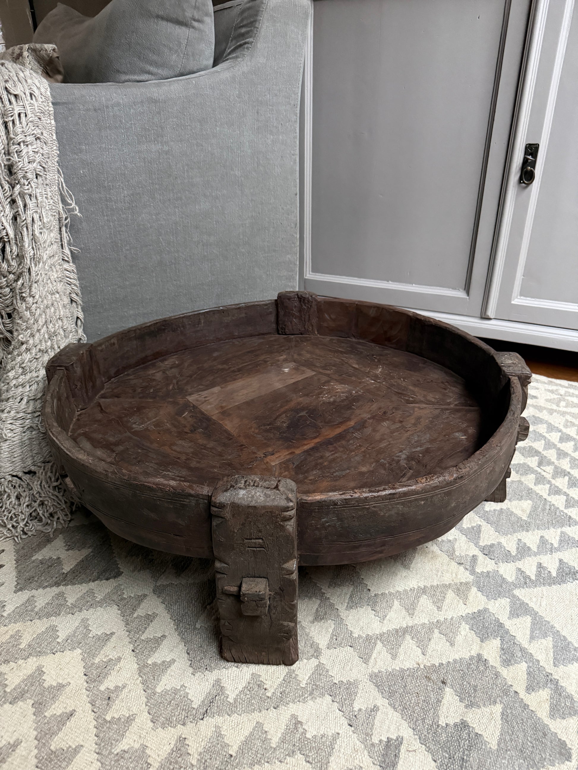 Authentieke, handgemaakte houten chakki tafel op vloerkleed in sober landelijk interieur