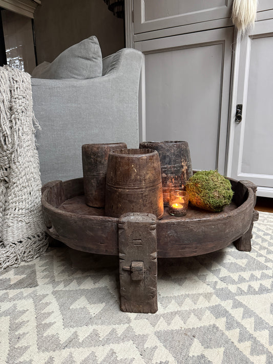 Authentieke houten chakki tafel met kaars en rustieke woondecoratie op vloerkleed in sober interieur