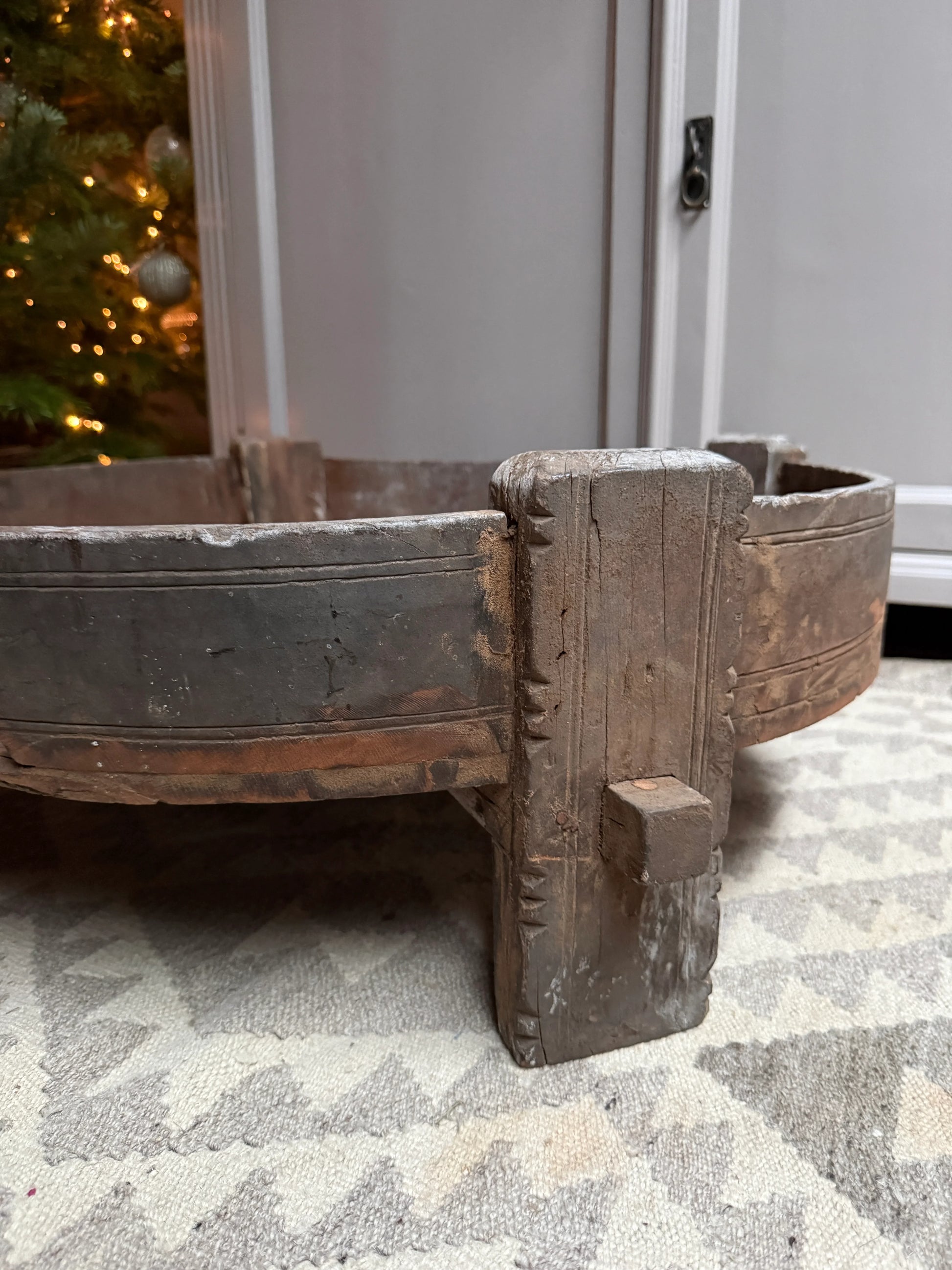 Detail van een handgemaakte, houten chakkitafel op grijs vloerkleed, landelijk interieur