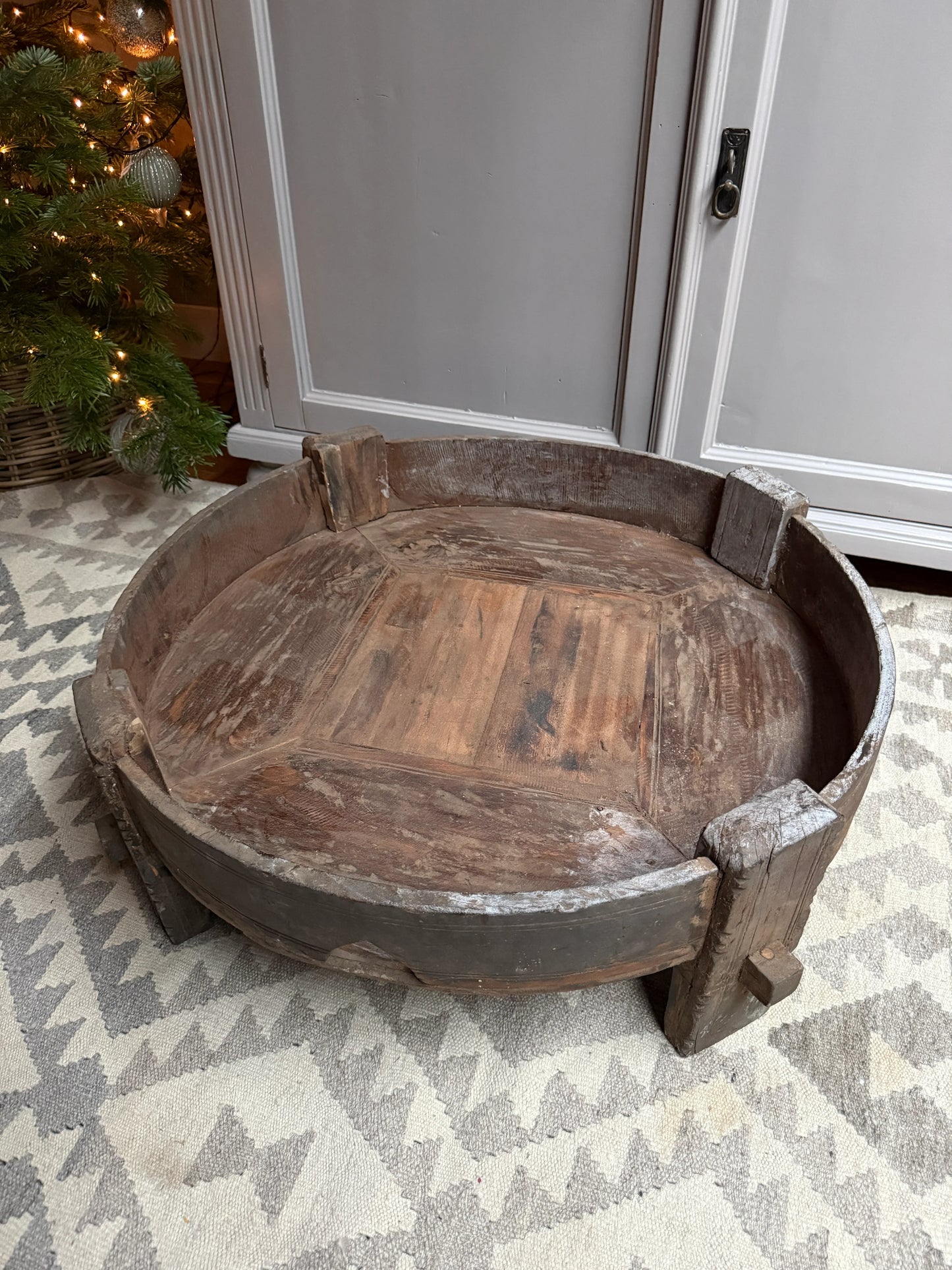 Authentieke houten chakki tafel op oosters vloerkleed, landelijke sobere woonaccessoire