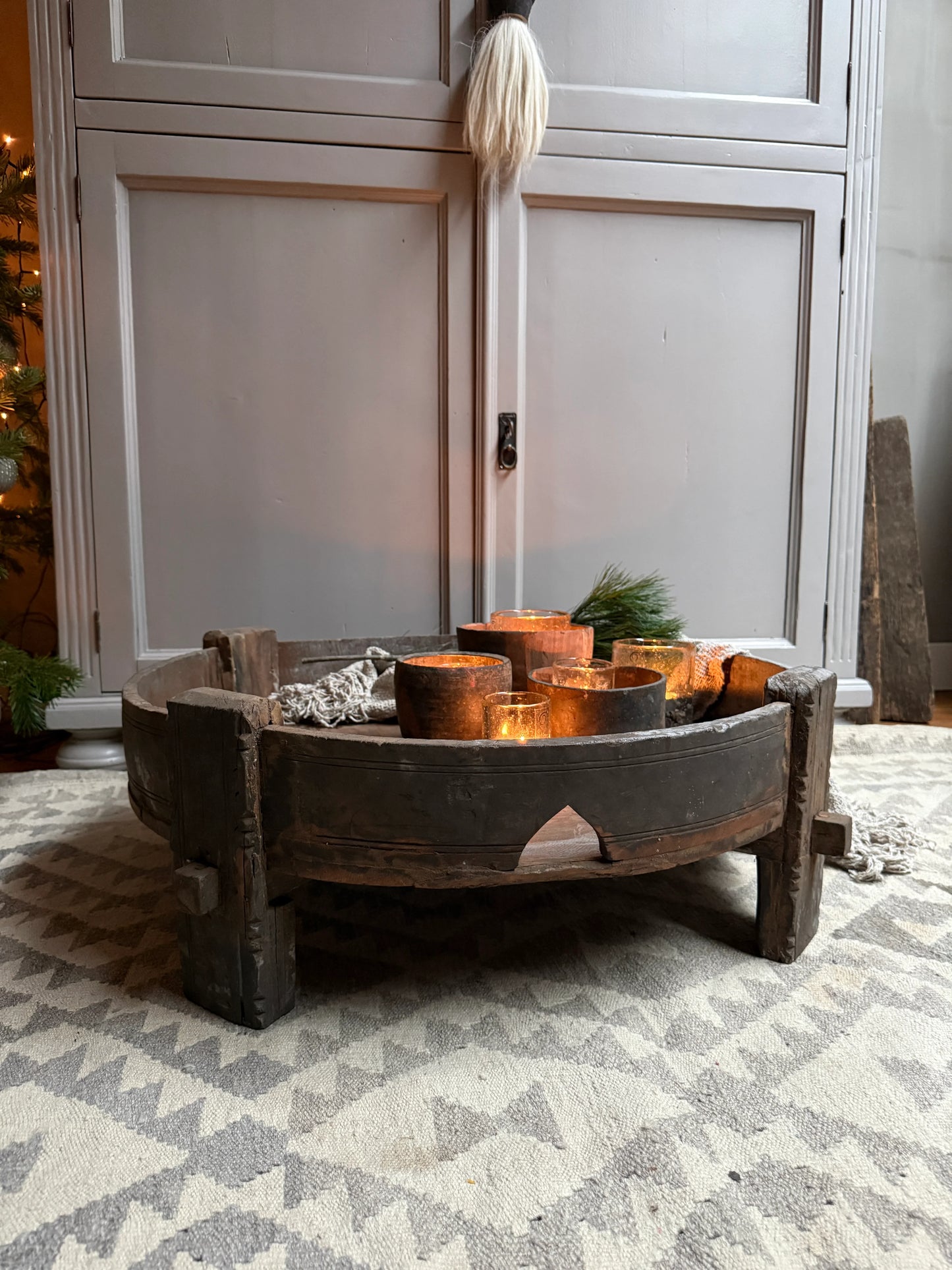 Handgemaakte Chakkitafel met landelijke kaarsen op wollen vloerkleed, sober interieur