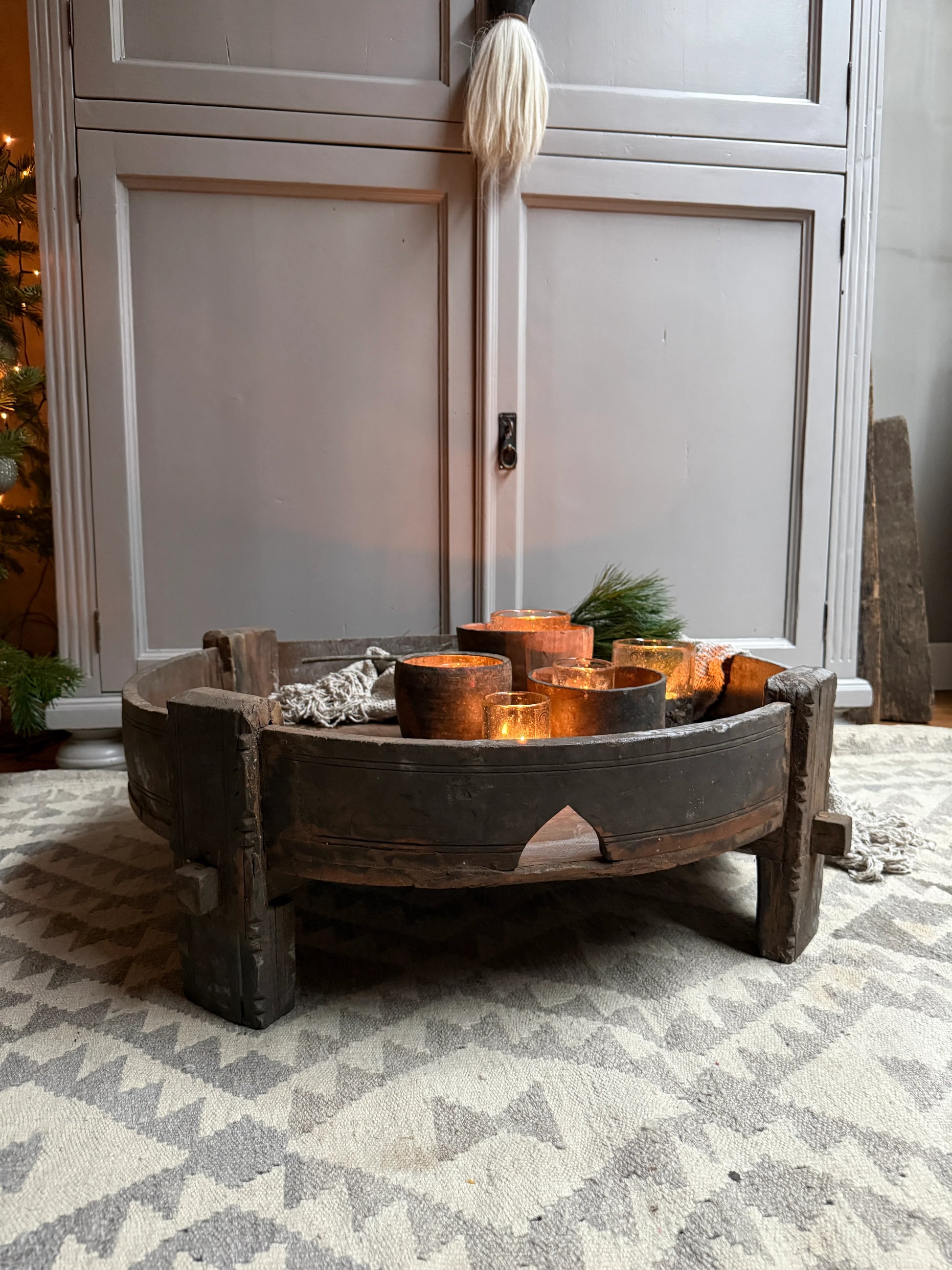 Handgemaakte Chakkitafel met landelijke kaarsen op wollen vloerkleed, sober interieur