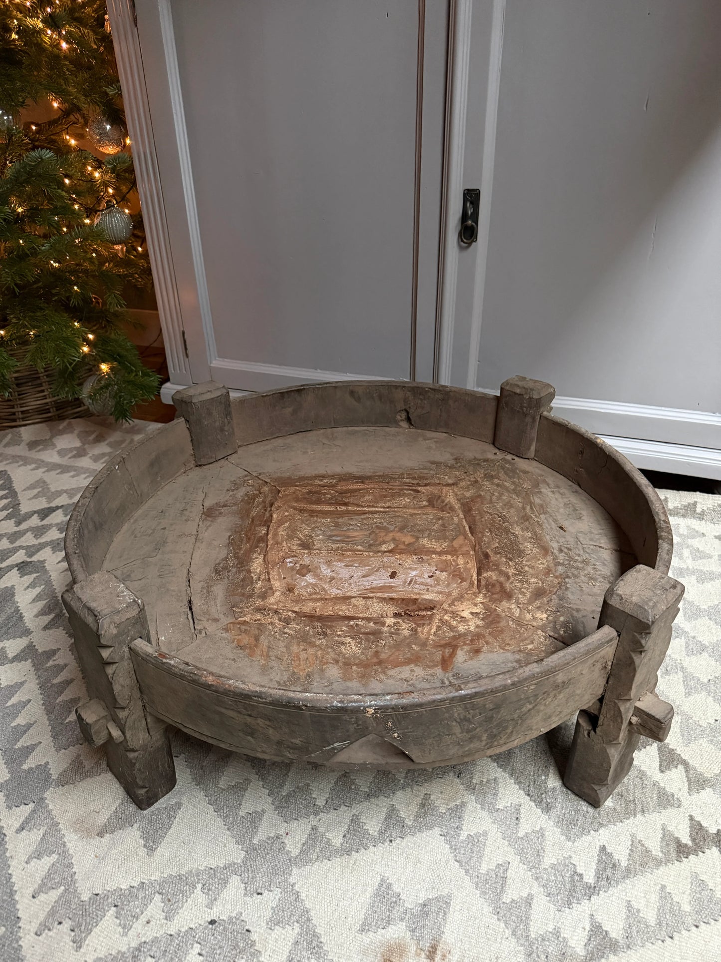 Authentieke, handgemaakte houten chakki tafel uit India op vloerkleed, sober landelijk interieur