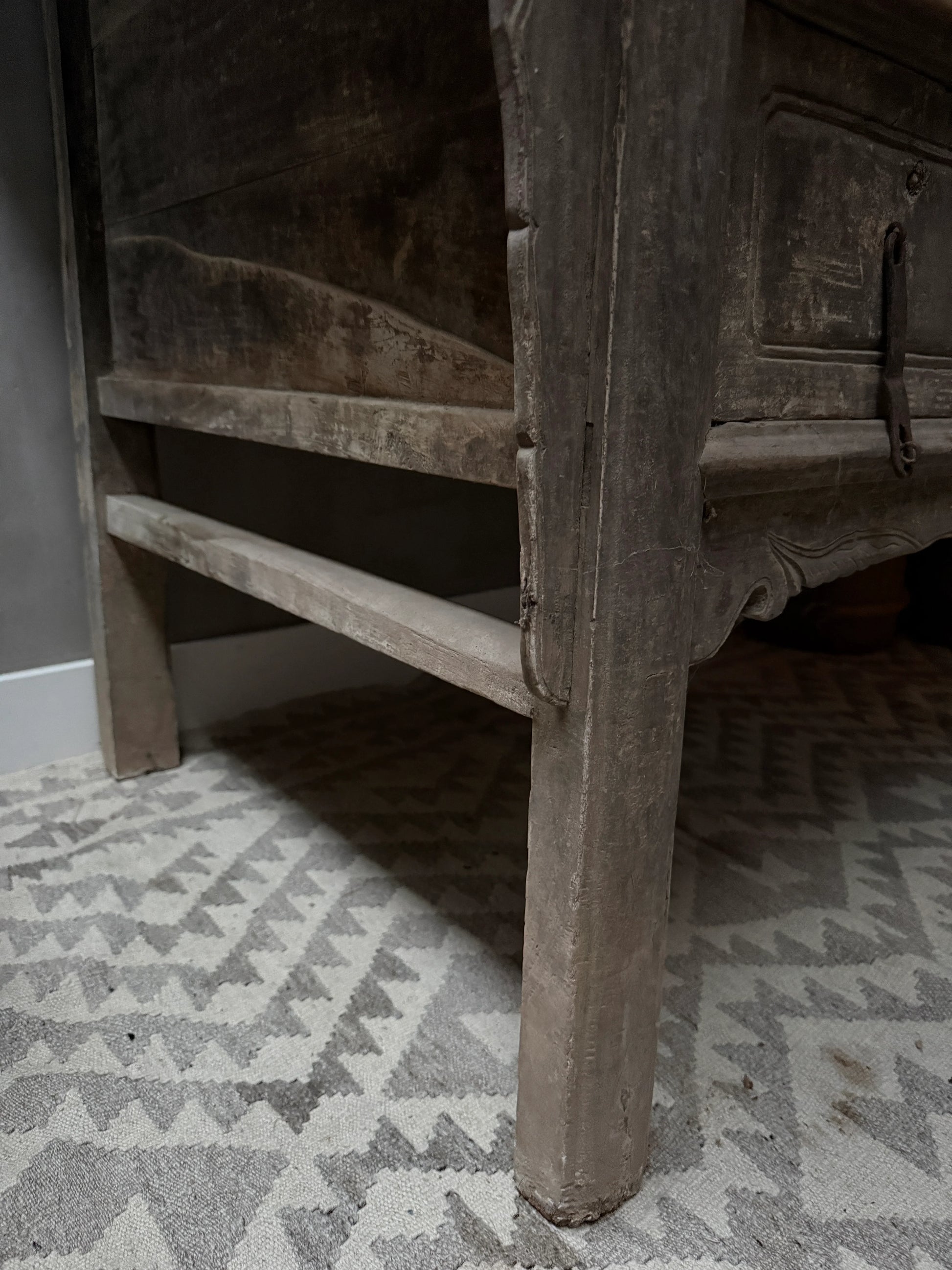 Detail van een authentieke, handgemaakte houten wandtafel op landelijk vloerkleed.