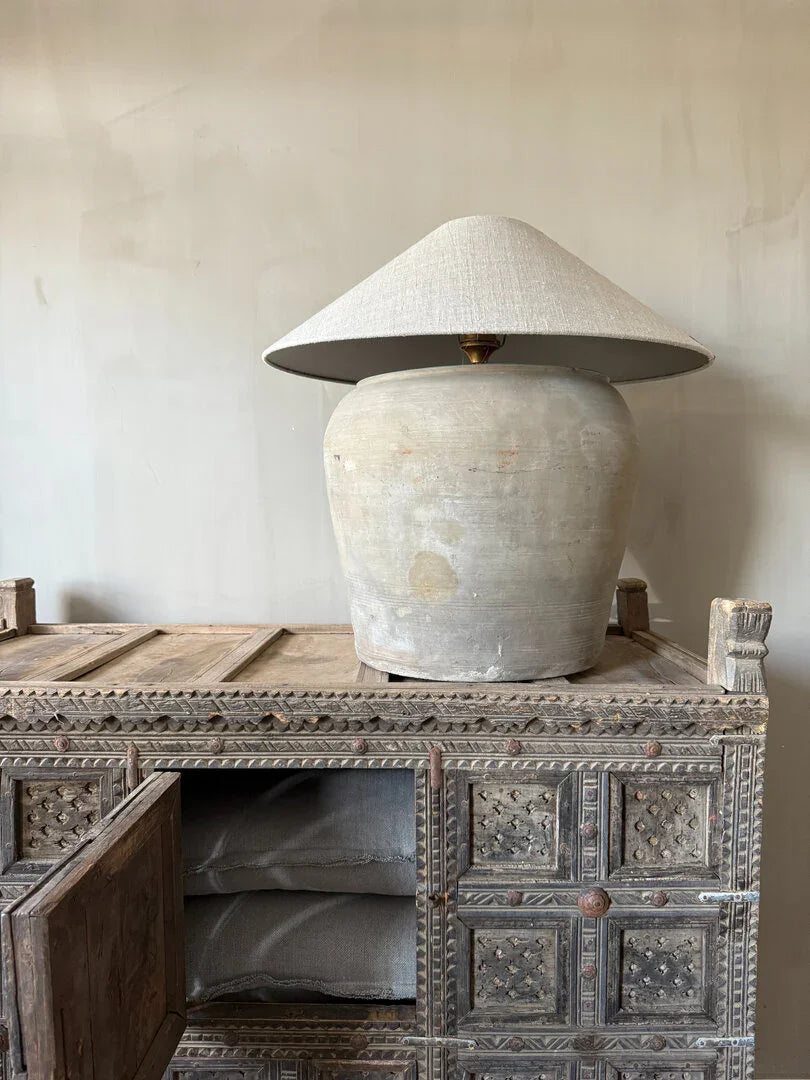 Authentieke houten damchiya kast met open deur en grote linnen tafellamp, landelijk interieur