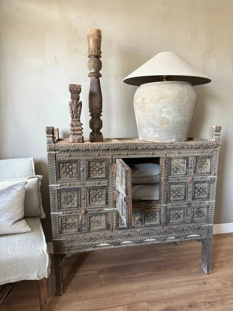 Authentieke houten damchiya kast met handgesneden details, keramische lamp en zuilen, sober interieur