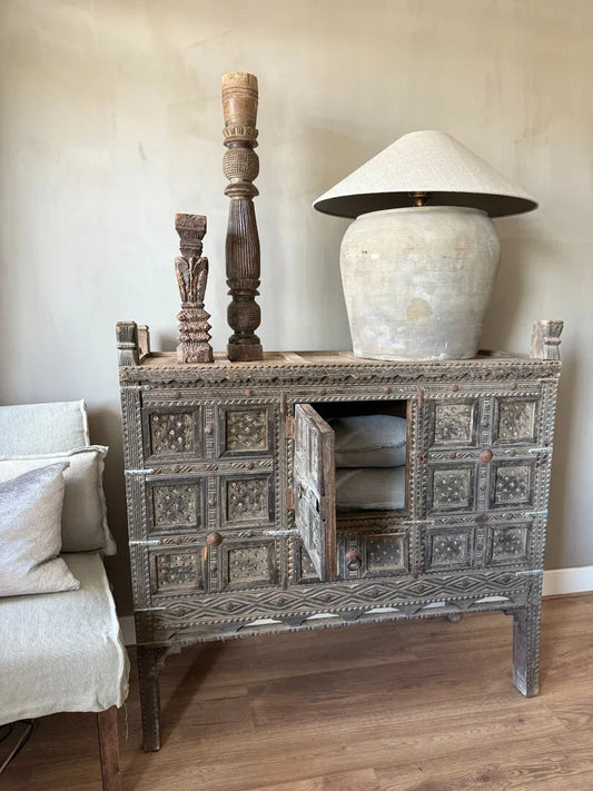 Authentieke houten damchiya kast met handgesneden details, keramische lamp en zuilen, sober interieur