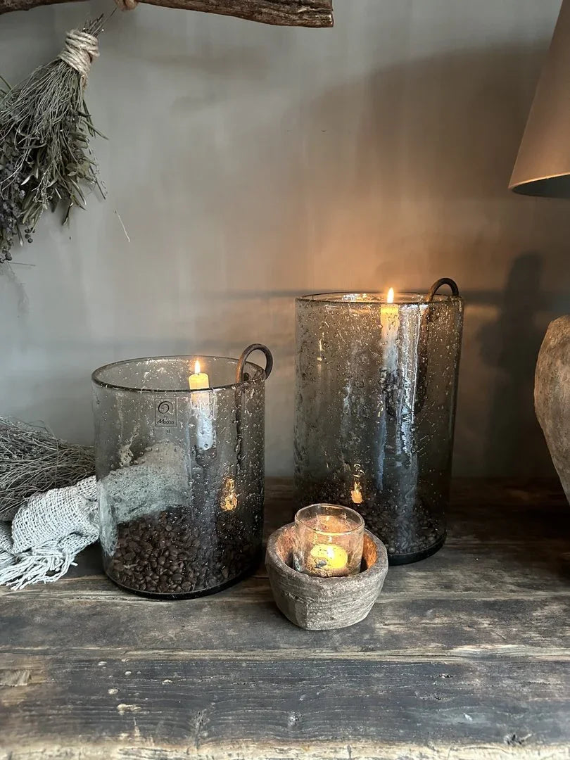 Landelijke sfeer met handgemaakte glazen windlichten, kaarsen en houten schaal op houten tafel