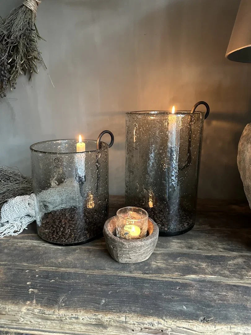 Handgemaakte glazen windlichten met brandende kaarsen op houten tafel, landelijk sober interieur