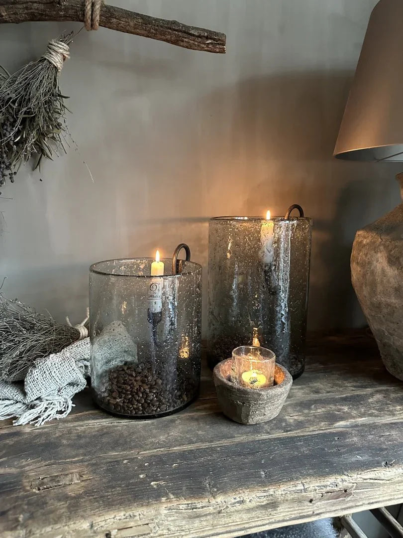 Sfeervolle handgemaakte glazen kandelaars met kaarsen op een houten tafel, landelijk sober interieur