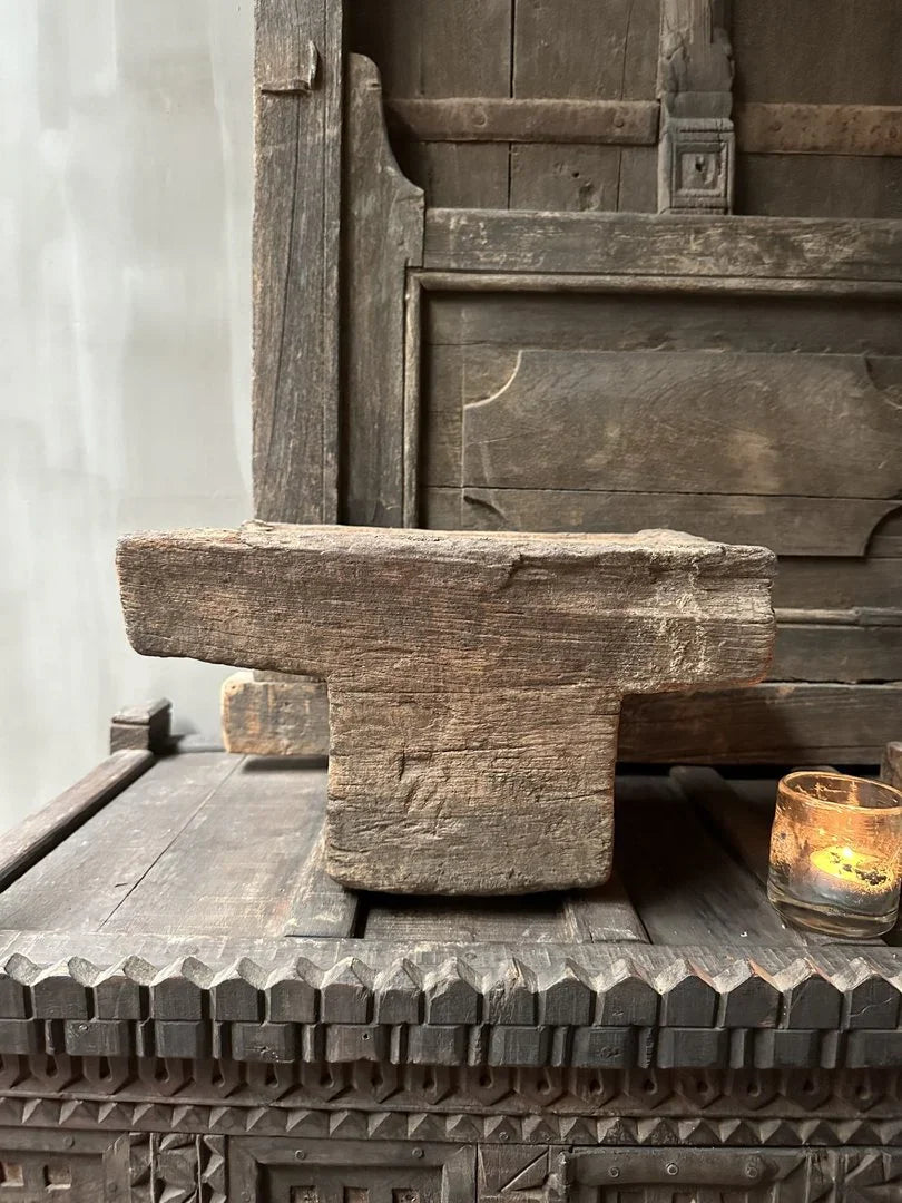 Authentieke, handgemaakte houten poer op een sobere houten tafel met sfeerlicht, landelijk interieur