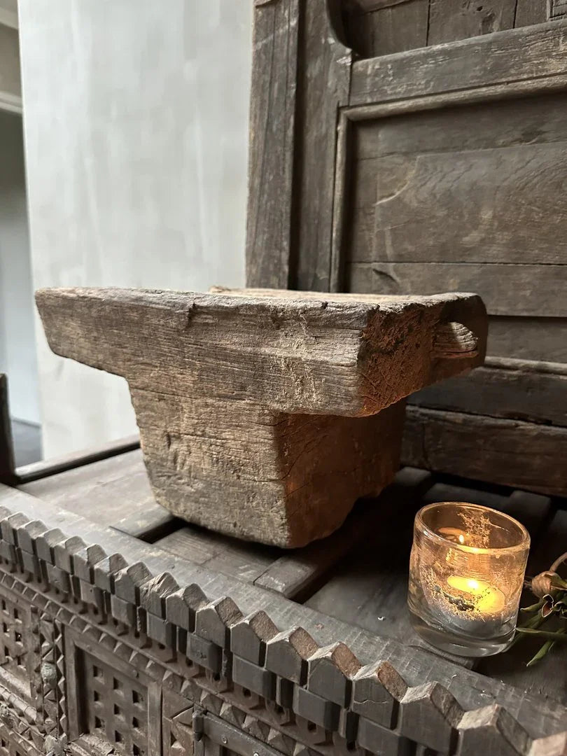 Authentieke handgemaakte houten poer op sobere kast, met brandend waxinelichtje, landelijk interieur