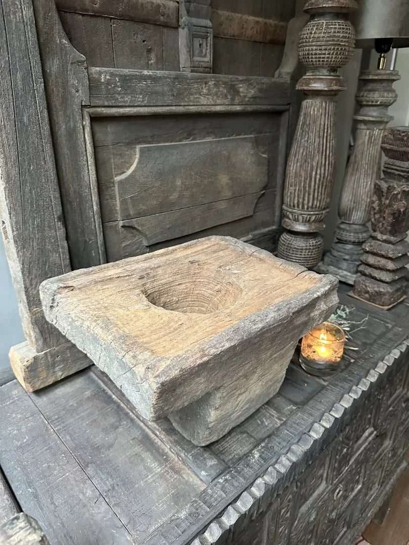 Authentieke handgemaakte houten poer uit India op sobere tafel met rustieke accessoires